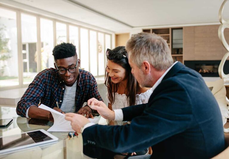 Young couple reviewing life insurance documents and household finances at a kitchen table.