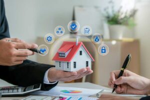 A middle-aged couple reviews household bills at a kitchen table with insurance paperwork and a laptop.