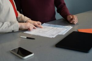 Person reviewing an insurance declaration page, policy booklet, and calculator on a kitchen table.