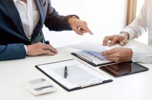 Driver reviews a rental agreement and auto insurance documents beside car keys on a vehicle dashboard.